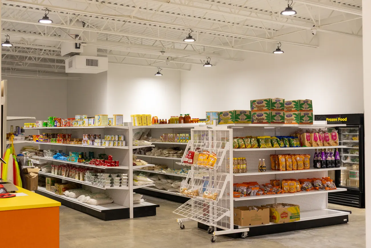Wide view of a grocery aisle at Afrimart stocked with rice, flour, canned goods, and plantain chips