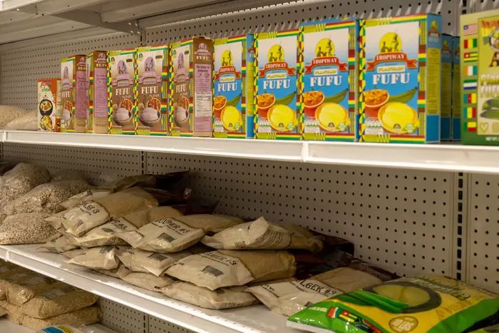 Boxes of Tropiway and African King plantain fufu flour lined up on a shelf at Afrimart
