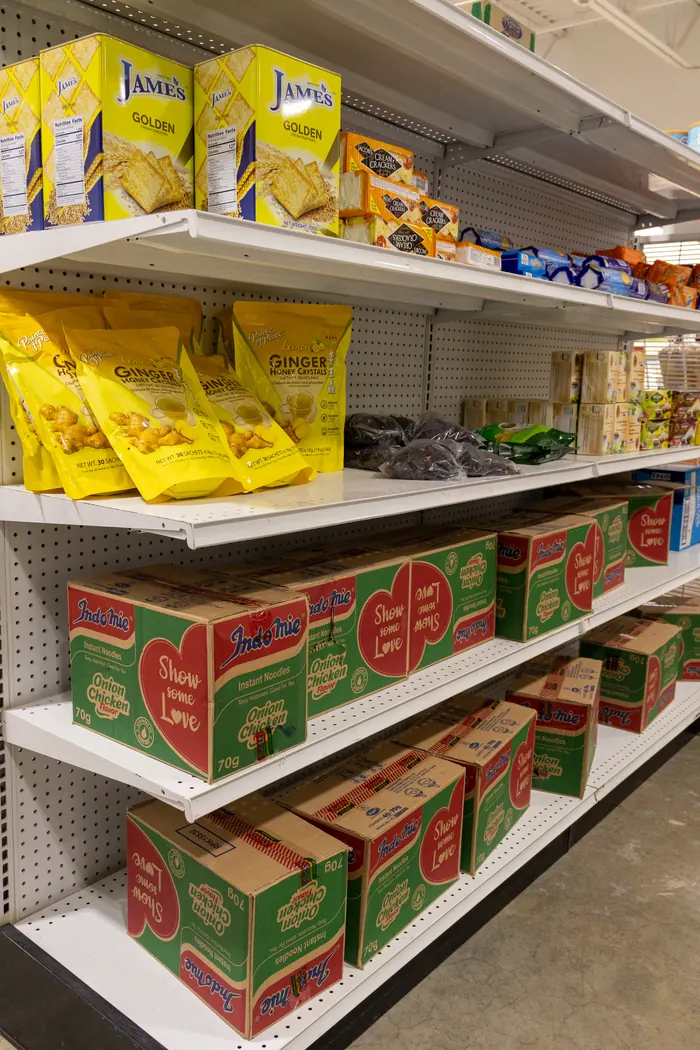 Shelf of crackers, ginger honey crystals, and Indomie instant noodle boxes at Afrimart